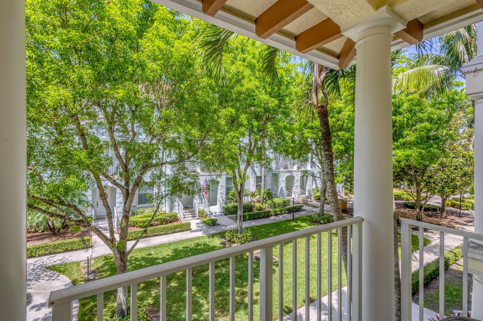 A view from a balcony overlooking a grassy courtyard with trees and residential buildings — 4320 Blowing Point Place, Jupiter FL 33458, JUPITER, FL