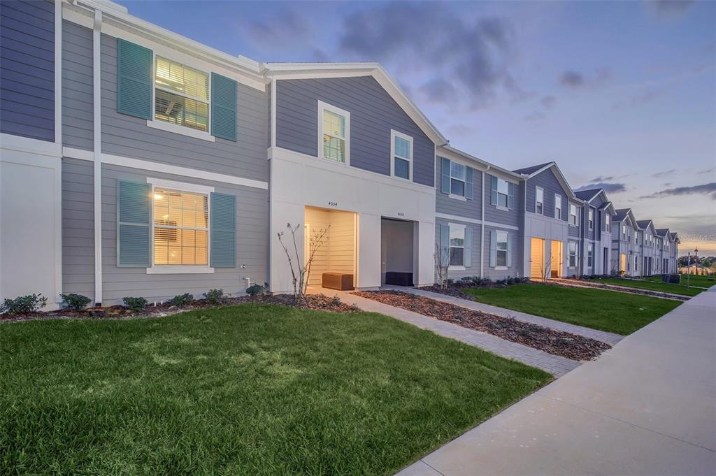 A row of two-story apartment buildings with grey siding, blue shutters, and paved walkways — 4034 LANA AVENUE, DAVENPORT, FL
