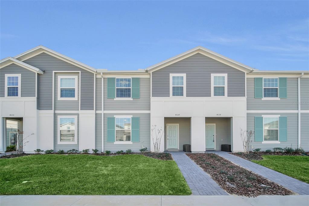 A two-story townhouse exterior features gray siding, teal shutters, and a paved walkway — 4034 LANA AVENUE, DAVENPORT, FL