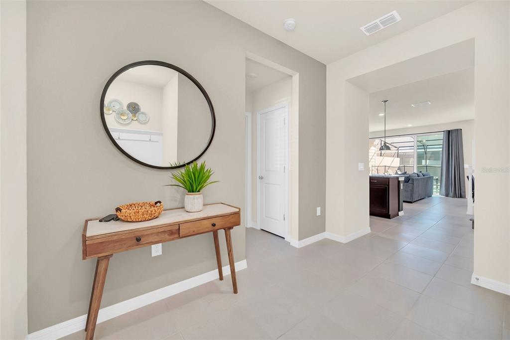 A hallway features a console table, a round mirror, and a view into the living area — 4034 LANA AVENUE, DAVENPORT, FL