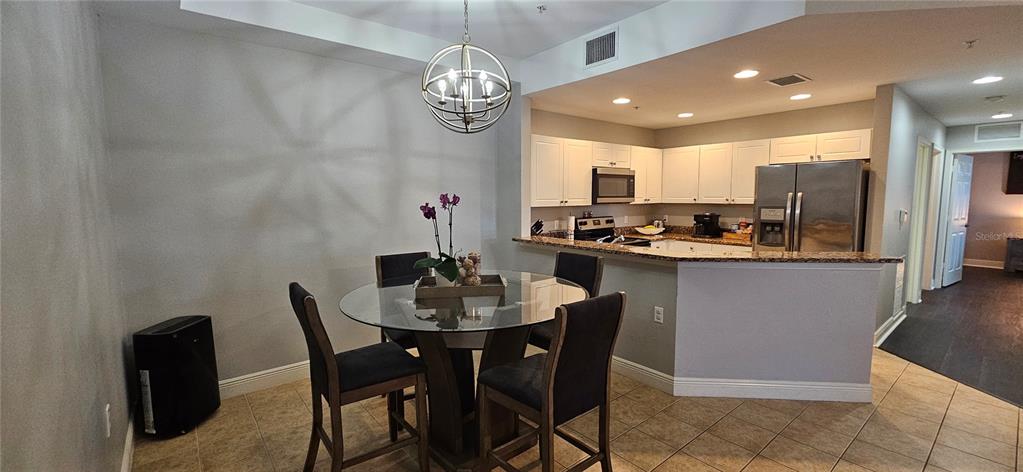 A dining area with a glass table and chairs sits adjacent to an open kitchen — 1502 SW 50TH STREET UNIT 104, CAPE CORAL, FL