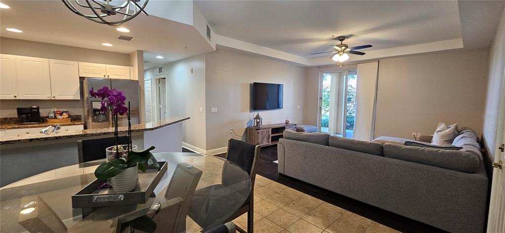 An open-concept living room and kitchen feature tile flooring, a gray sectional, and white cabinetry — 1502 SW 50TH STREET UNIT 104, CAPE CORAL, FL