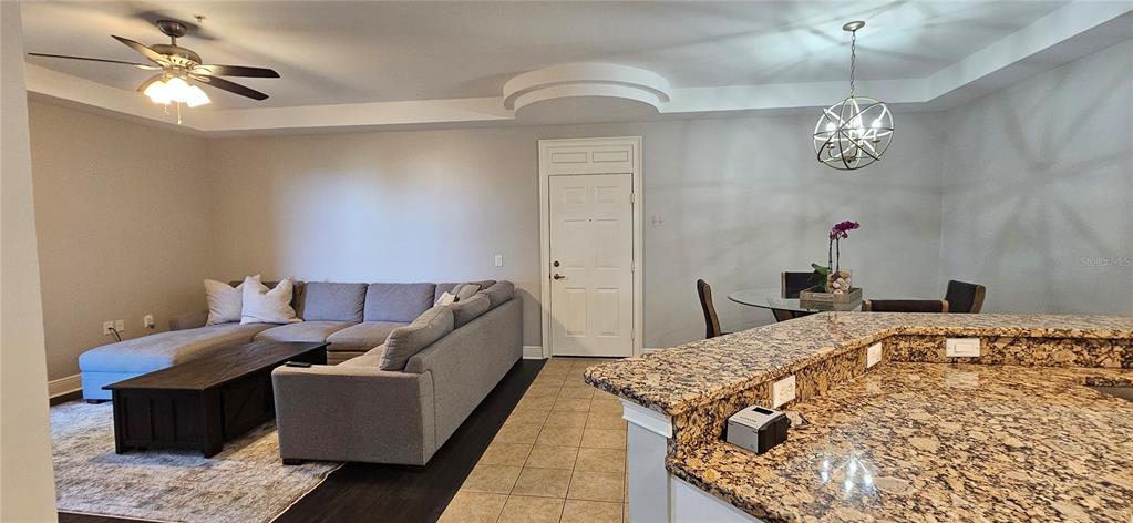 A living room and dining area feature a sectional sofa, granite countertops, and ceiling fans — 1502 SW 50TH STREET UNIT 104, CAPE CORAL, FL