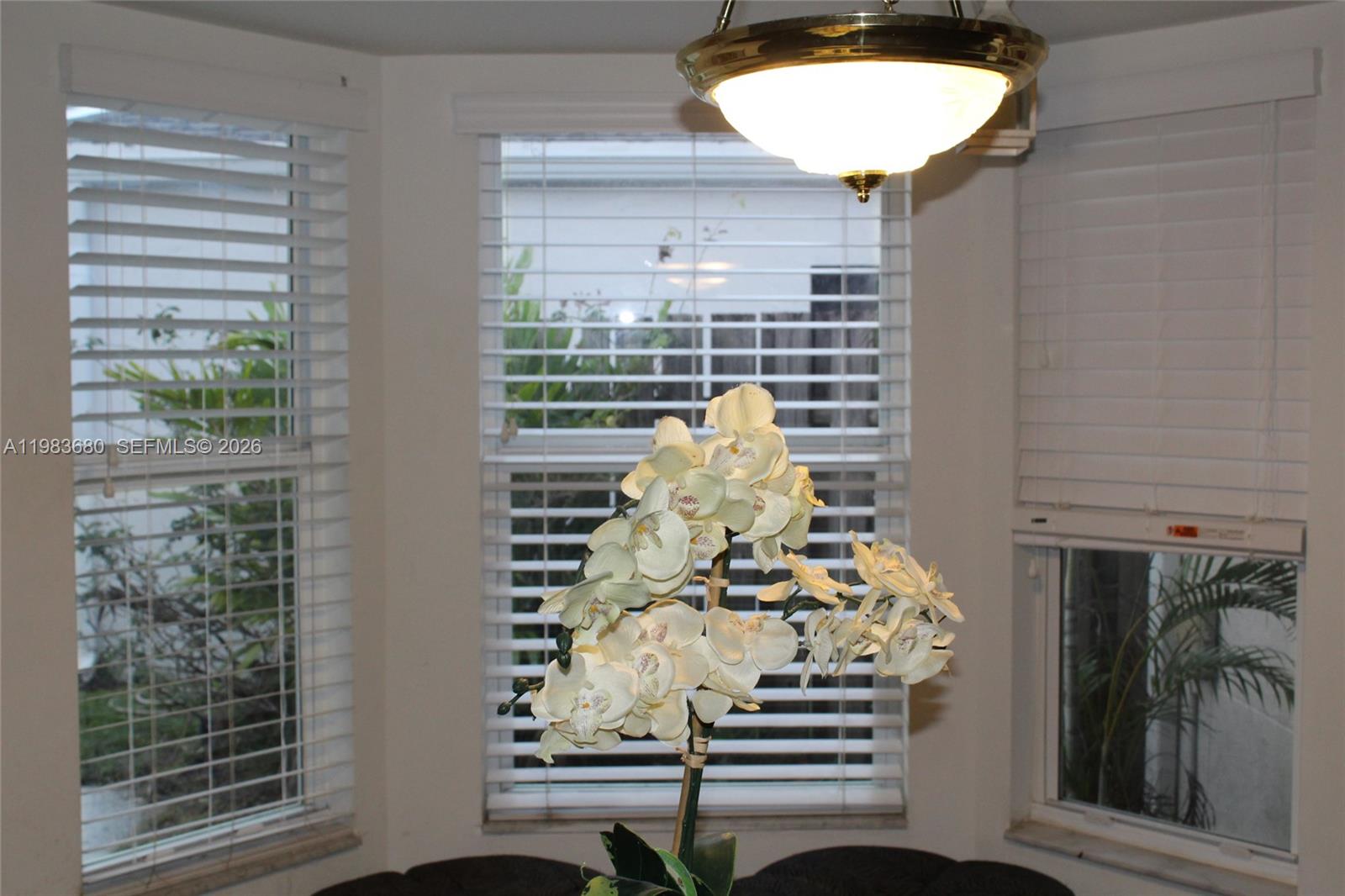 A dining area features a bay window with white blinds and a central orchid centerpiece — 9818 SW 222nd Ter, Cutler Bay FL 33190, CUTLER BAY, FL