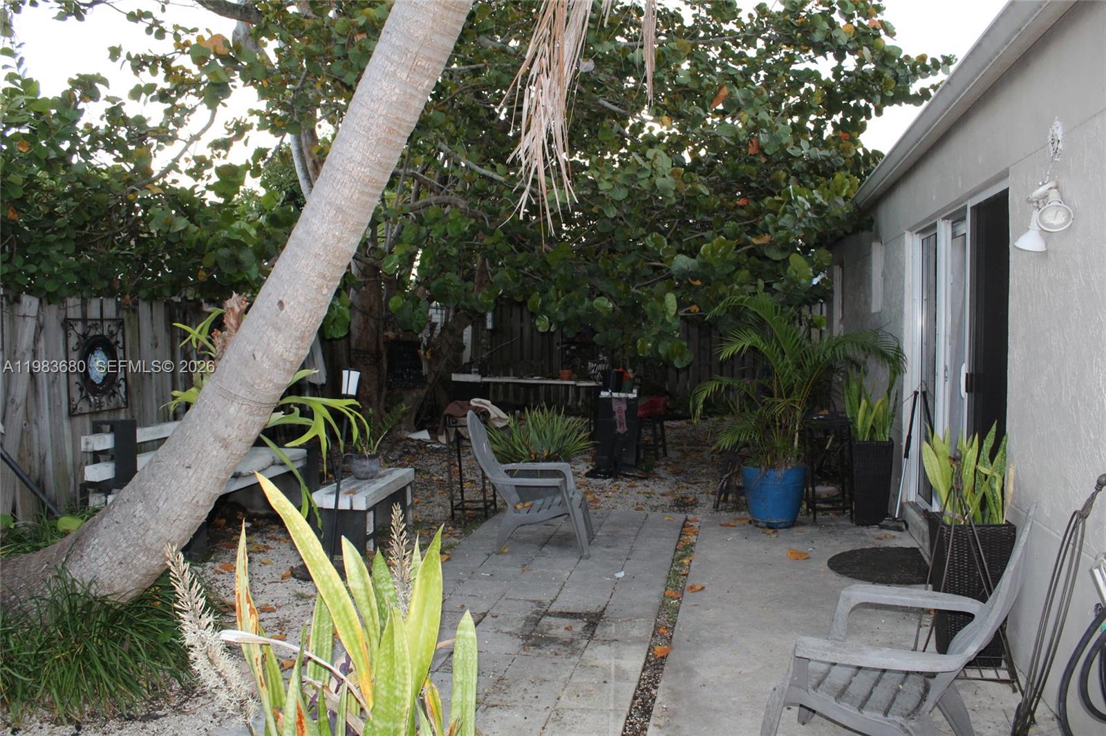 A backyard patio features a concrete slab, stone pavers, potted plants, and a large tree — 9818 SW 222nd Ter, Cutler Bay FL 33190, CUTLER BAY, FL
