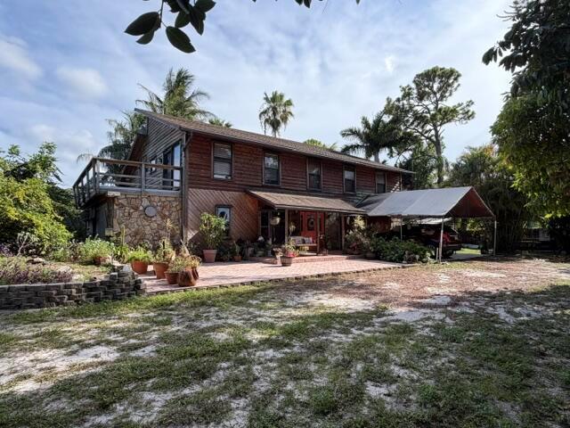 A two-story wooden house with a stone base, a brick patio, and a metal carport — 9219 Nickels, Boynton Beach FL 33436, BOYNTON BEACH, FL