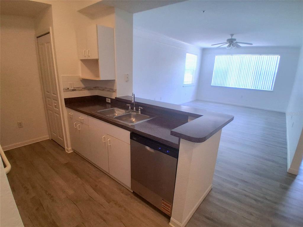 A kitchen with white cabinets and dark countertops overlooks an open living area — 17108 CARRINGTON PARK DRIVE UNIT 707, TAMPA, FL