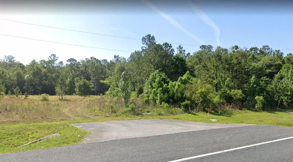 A paved driveway leads to a grassy, wooded vacant lot under a clear blue sky — 0 BROAD STREET, BROOKSVILLE, FL