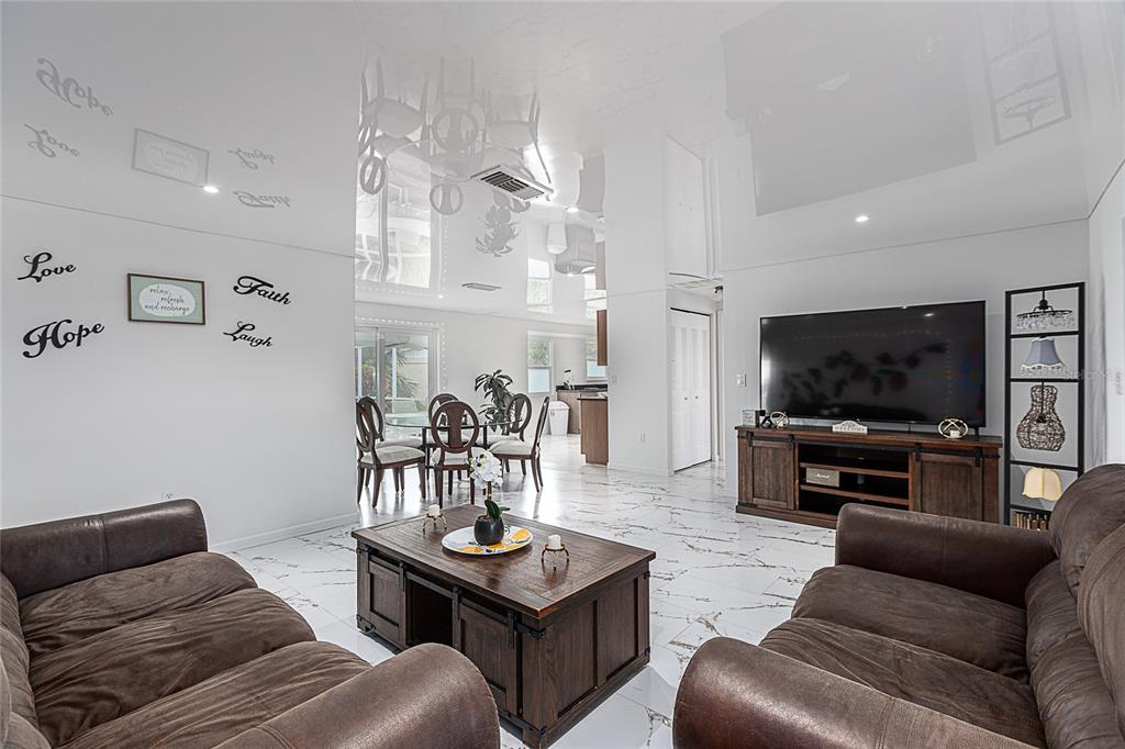 A living room with brown leather sofas, a wooden coffee table, and glossy white floors — 295 ANNAPOLIS LANE, ROTONDA WEST, FL