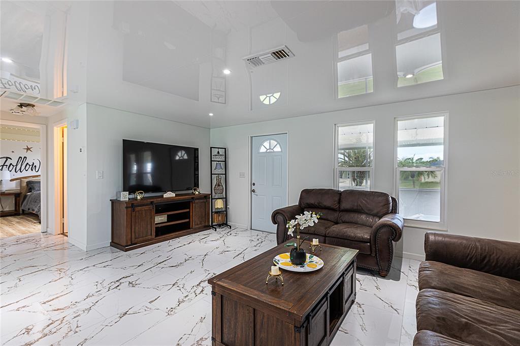 A living room features white marble-look tile floors, a glossy ceiling, and brown leather furniture — 295 ANNAPOLIS LANE, ROTONDA WEST, FL