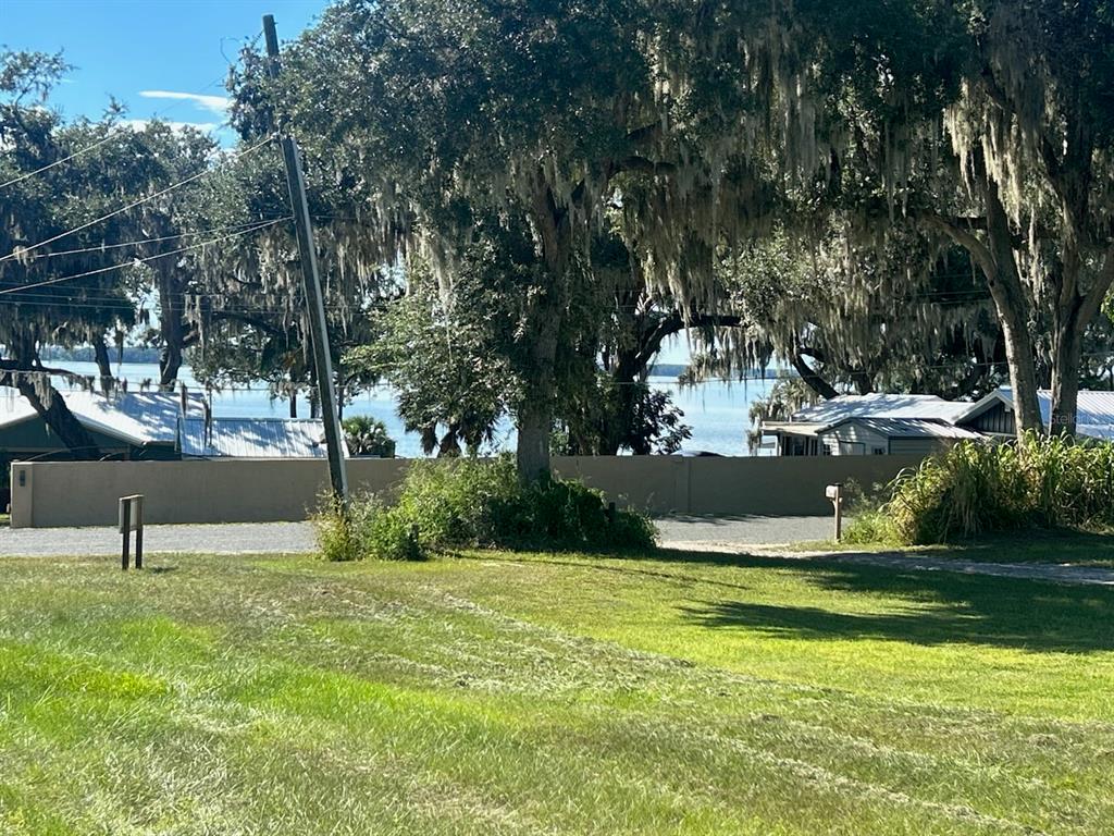 A view of a lake from a grassy yard with large trees and nearby houses — 15365 SE 140TH AVENUE ROAD, WEIRSDALE, FL