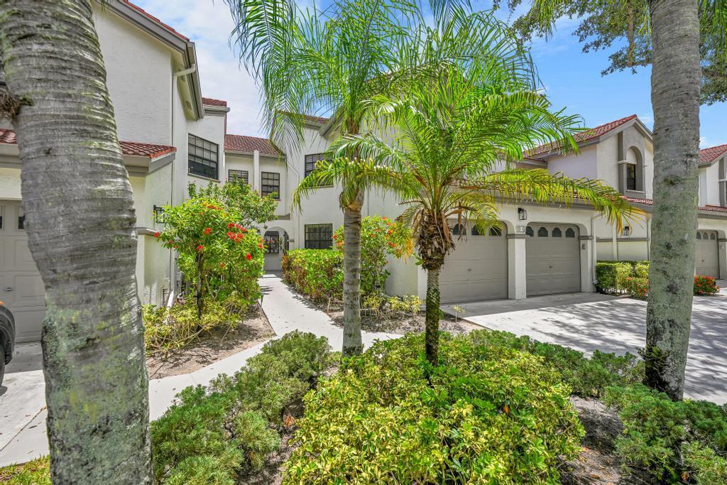 A multi-story townhouse exterior features a palm tree, a paved walkway, and attached garages — 5290 Europa Drive # B, Boynton Beach FL 33437, BOYNTON BEACH, FL