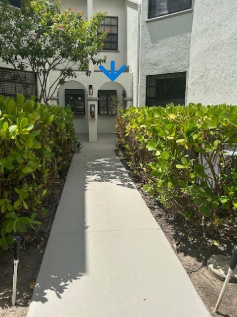 A concrete walkway leads to a building entrance featuring two arched openings and mailboxes — 5290 Europa Drive # B, Boynton Beach FL 33437, BOYNTON BEACH, FL