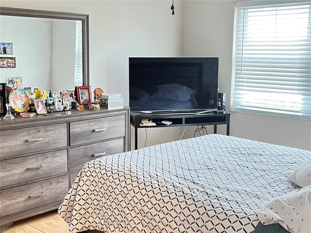 A bedroom features a wooden dresser with a mirror, a television on a stand, and a bed — 456 WINDMEADOWS STREET UNIT 456, ALTAMONTE SPRINGS, FL