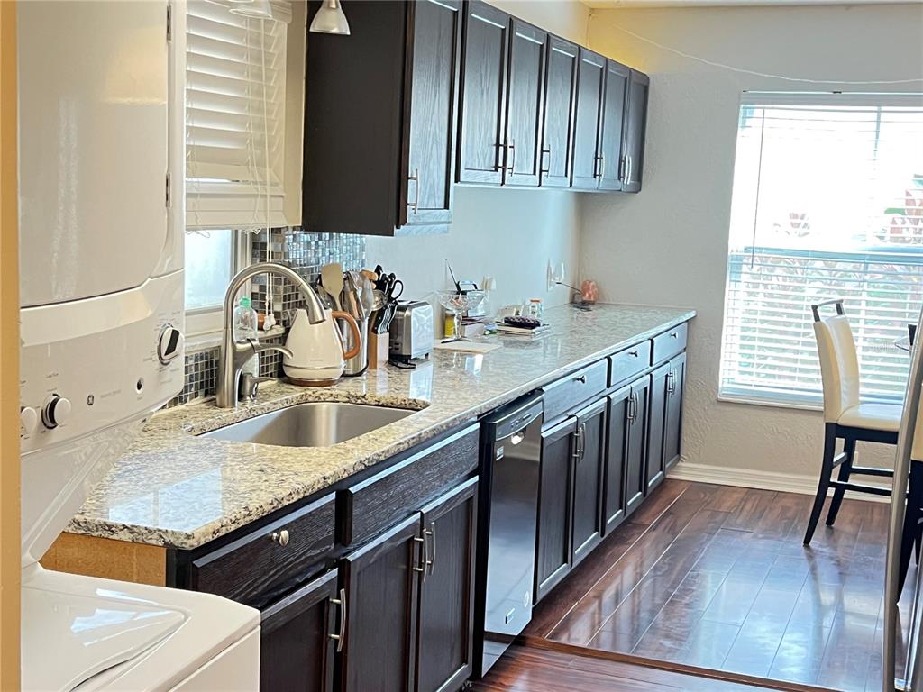 A kitchen features dark wood cabinets, granite countertops, stainless steel appliances, and wood flooring — 456 WINDMEADOWS STREET UNIT 456, ALTAMONTE SPRINGS, FL