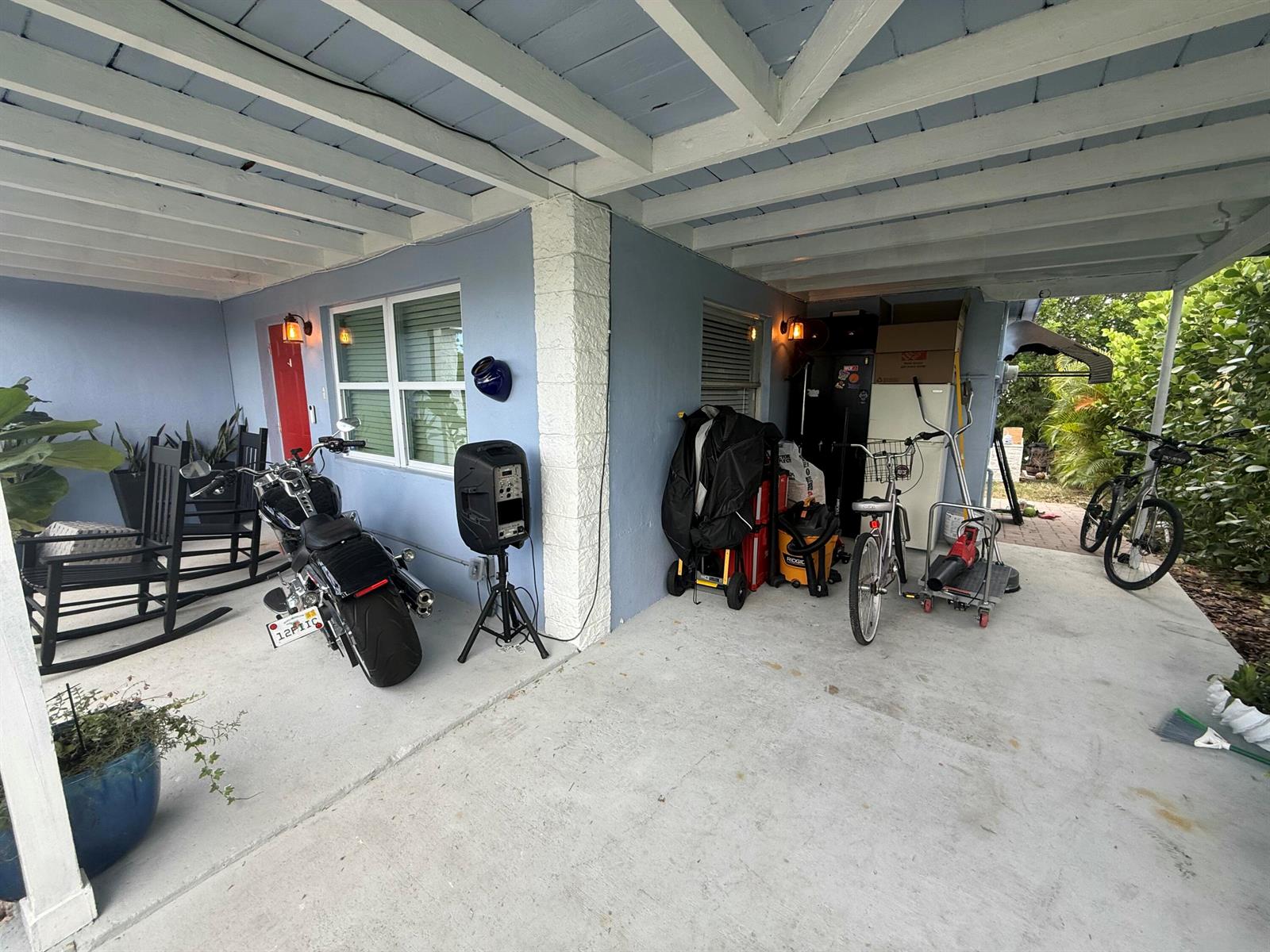 A backyard features a grassy lawn, a stone fire pit, and a hanging shade sail — 1209 W 34th Street, Riviera Beach FL 33404, RIVIERA BEACH, FL