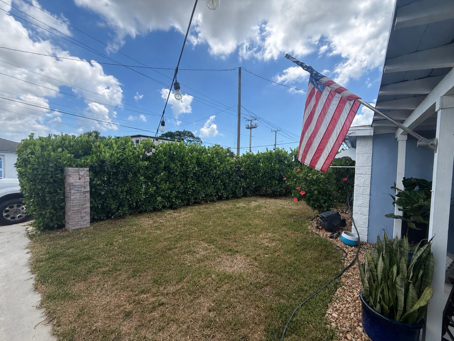 A backyard patio features a stone walkway, outdoor kitchen, and seating area under palm trees — 1209 W 34th Street, Riviera Beach FL 33404, RIVIERA BEACH, FL