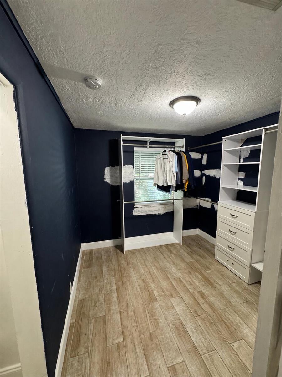 A bedroom features light wood-look flooring, a low-profile bed, a television, and a pet bed — 1209 W 34th Street, Riviera Beach FL 33404, RIVIERA BEACH, FL