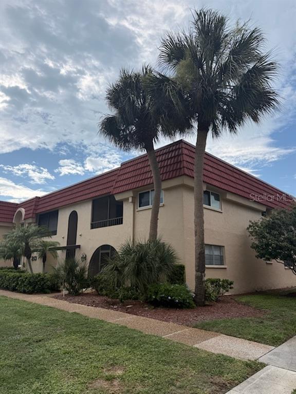 A two-story apartment building with a red tile roof and palm trees in the front — 213 RUBENS DRIVE UNIT H, NOKOMIS, FL