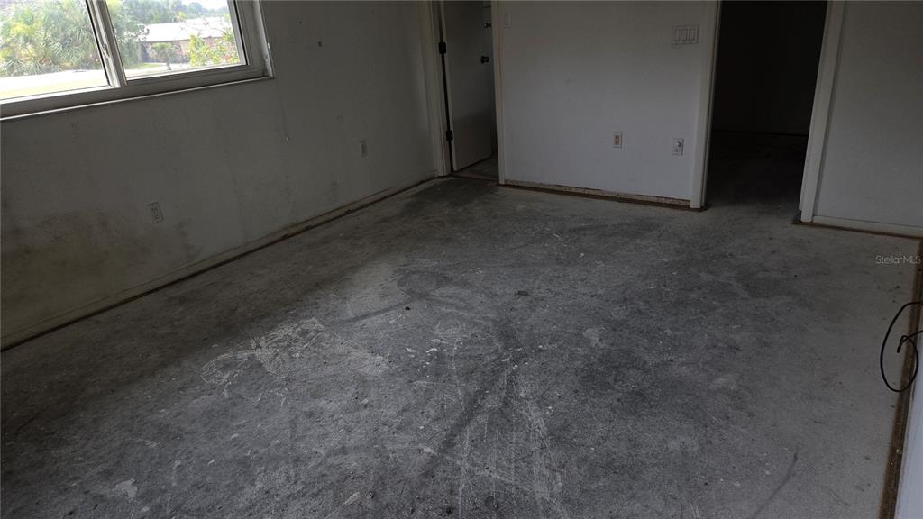 An empty room features white walls, a window, and a bare concrete subfloor — 213 RUBENS DRIVE UNIT H, NOKOMIS, FL