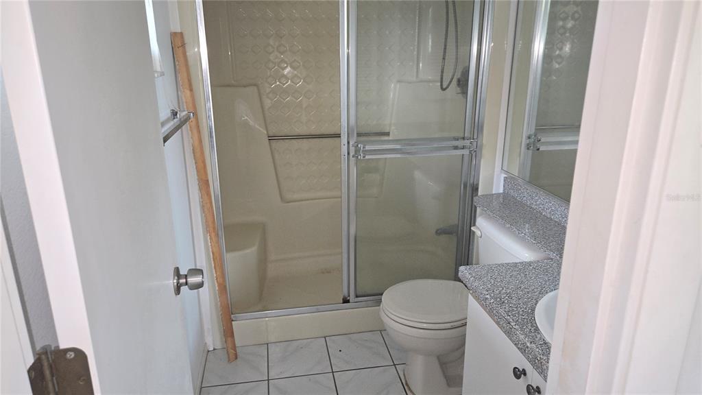A bathroom features a walk-in shower with sliding glass doors, a toilet, and a vanity — 213 RUBENS DRIVE UNIT H, NOKOMIS, FL