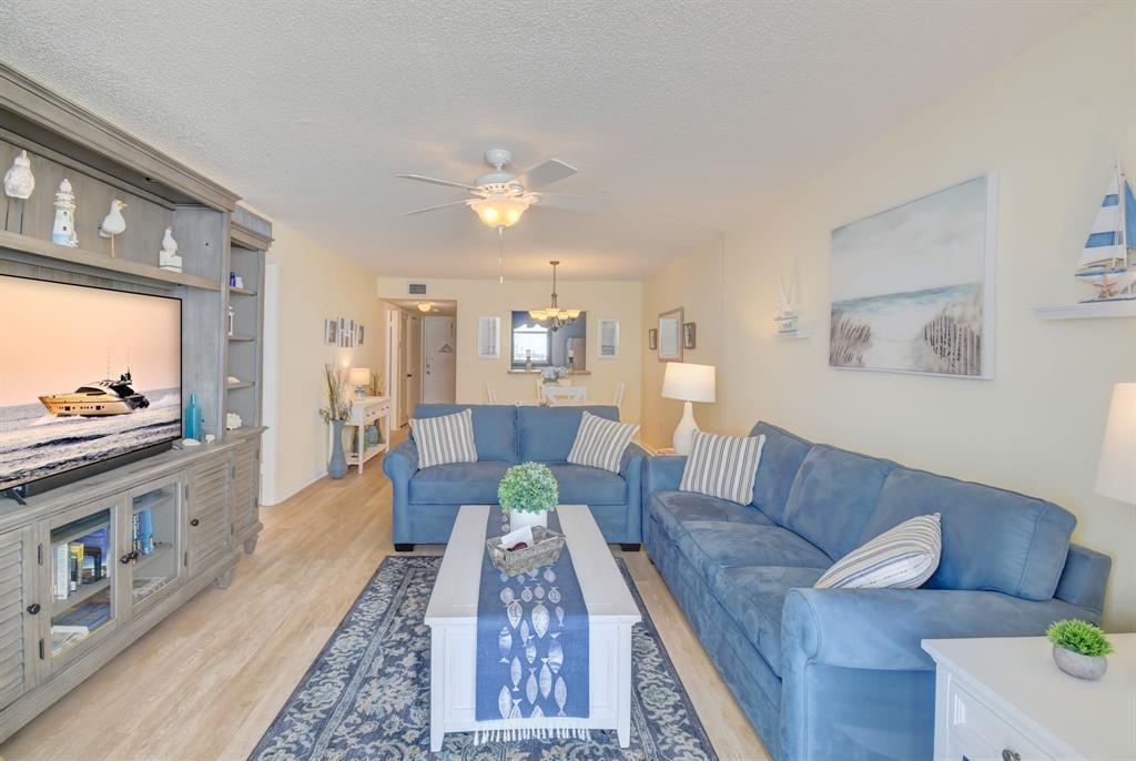 A living room features blue sofas, a white coffee table, and a large media console — 9940 S Ocean Drive # 505, Jensen Beach FL 34957, JENSEN BEACH, FL