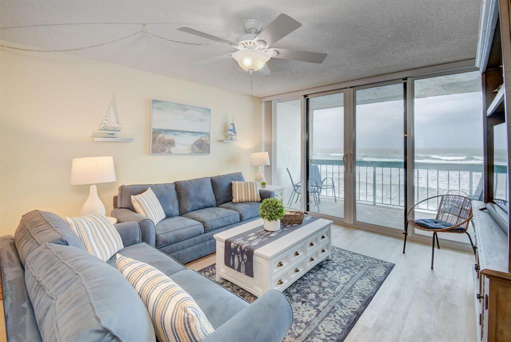 A living room with blue sofas, a white coffee table, and a balcony overlooking the ocean — 9940 S Ocean Drive # 505, Jensen Beach FL 34957, JENSEN BEACH, FL