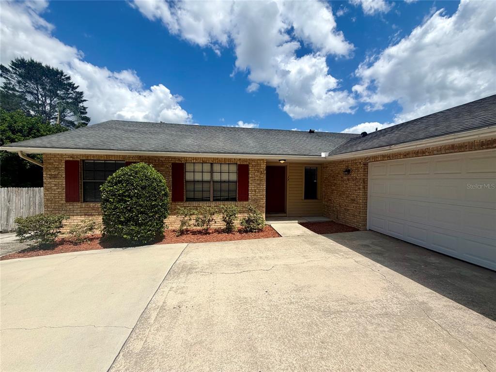 A single-story brick house features a white garage door, red shutters, and a concrete driveway — 37 HOLLOW BRANCH ROAD, APOPKA, FL