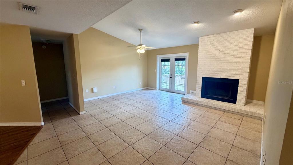 A living room features beige tile floors, a white brick fireplace, and French doors — 37 HOLLOW BRANCH ROAD, APOPKA, FL