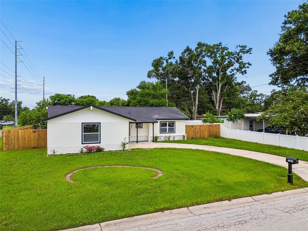 A single-story house with white siding, a dark roof, and a curved concrete driveway — 7802 N MATANZAS AVENUE, TAMPA, FL