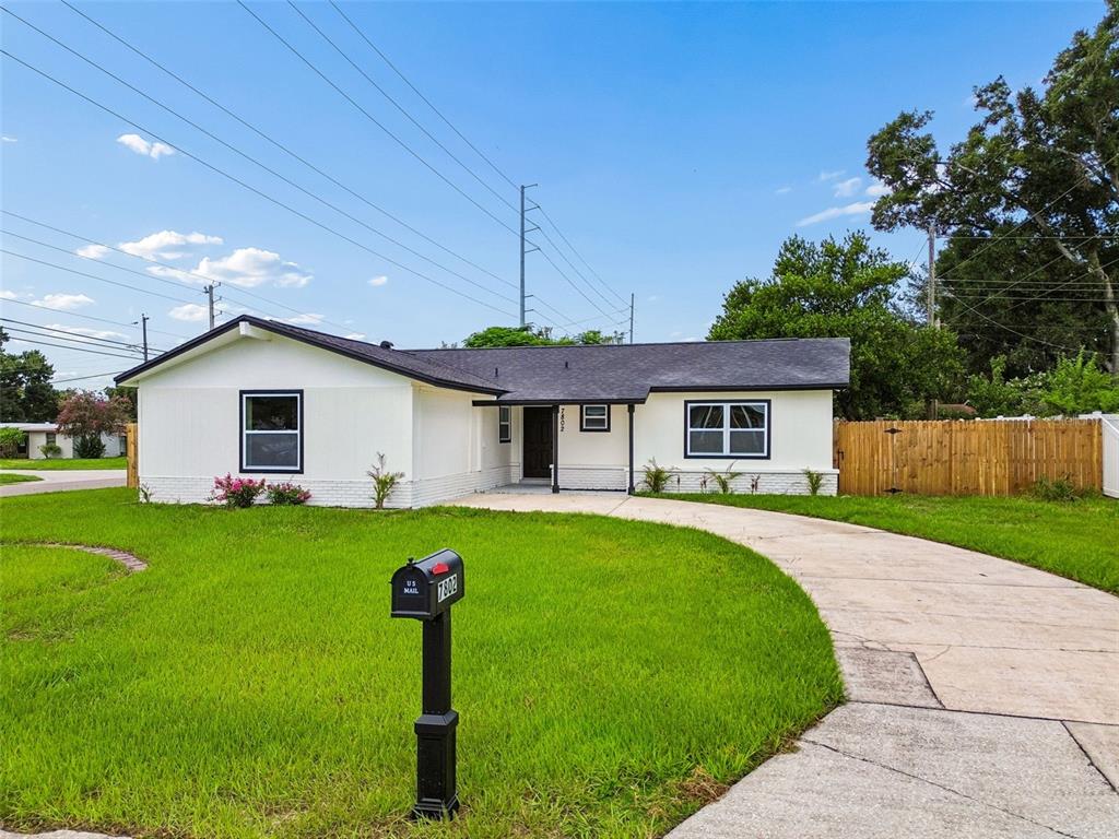 A single-story white house with a dark roof and a curved concrete driveway — 7802 N MATANZAS AVENUE, TAMPA, FL