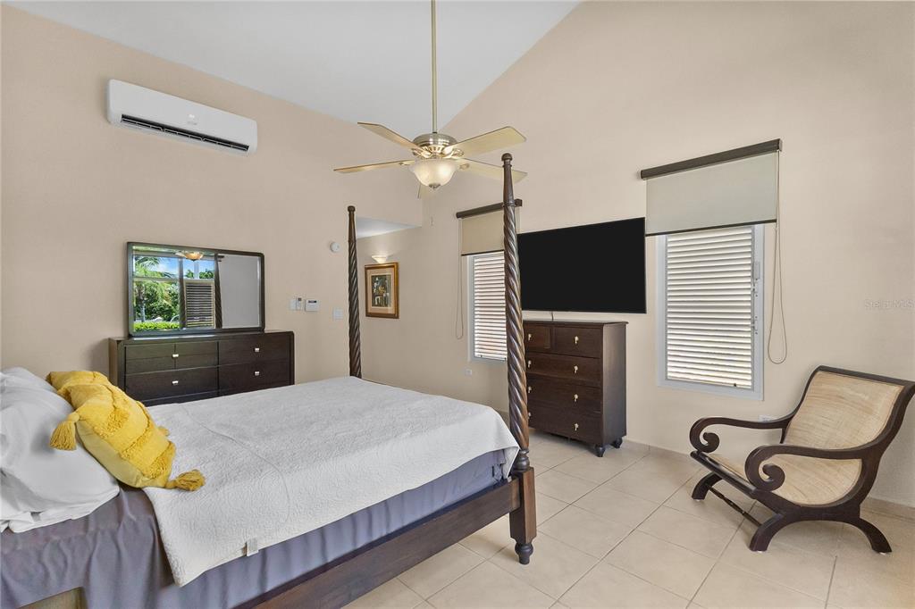 A bedroom features a four-poster bed, a ceiling fan, a dresser, and a television — 34 BIRDIE LN, HUMACAO, PR