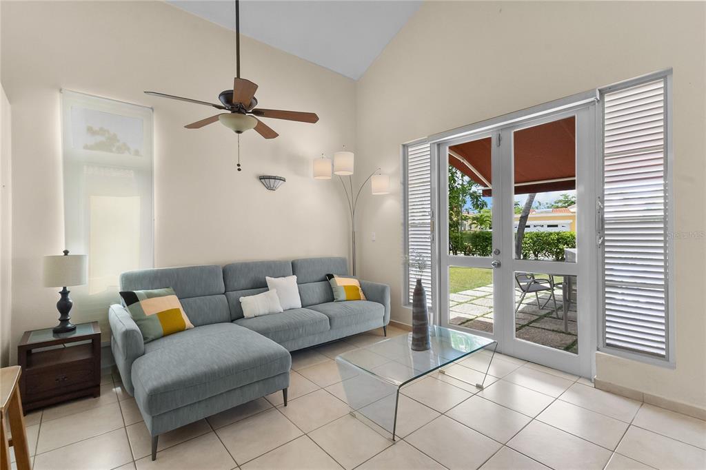 A living room features a blue sectional sofa, glass coffee table, and glass patio doors — 34 BIRDIE LN, HUMACAO, PR