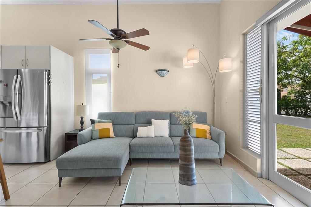 A living room features a blue sectional sofa, a glass coffee table, and a refrigerator — 34 BIRDIE LN, HUMACAO, PR