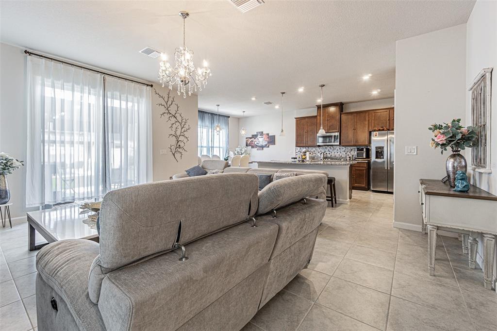 A living room with a grey sofa opens into a kitchen with wooden cabinets — 11904 THORNCREST DRIVE, SPRING HILL, FL