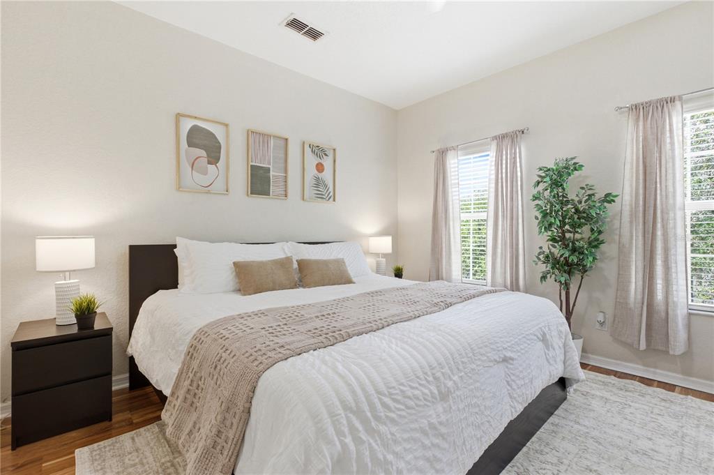 A bedroom features a bed with white bedding, a tan runner, and three framed wall prints — 2420 CARAVELLE CIRCLE, KISSIMMEE, FL