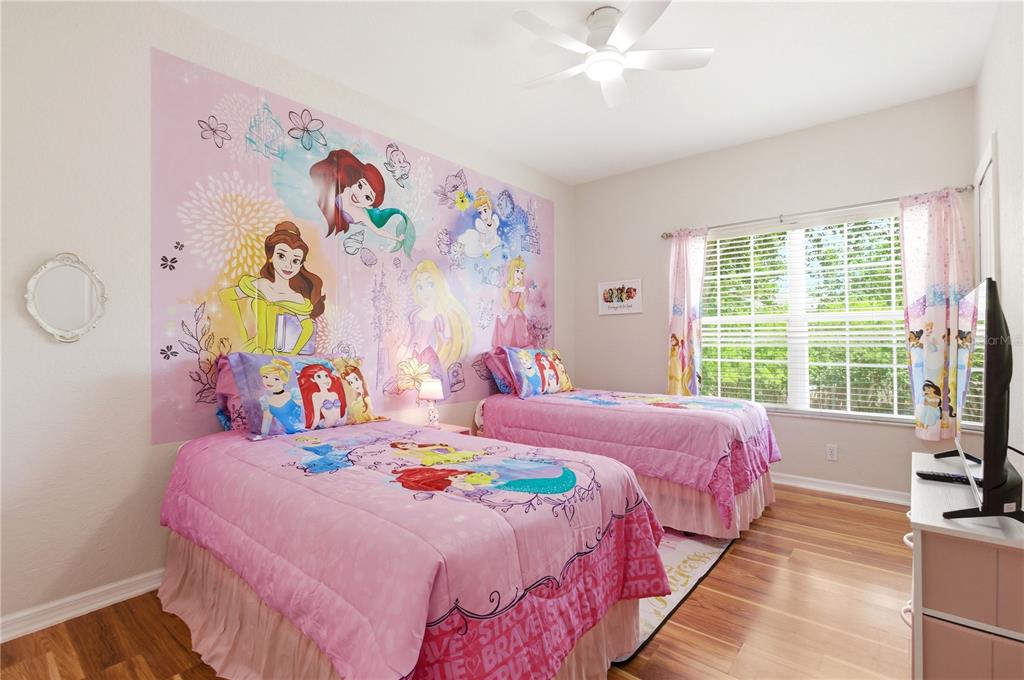 A bedroom features a bed with a textured comforter, two nightstands, and a large window — 2420 CARAVELLE CIRCLE, KISSIMMEE, FL
