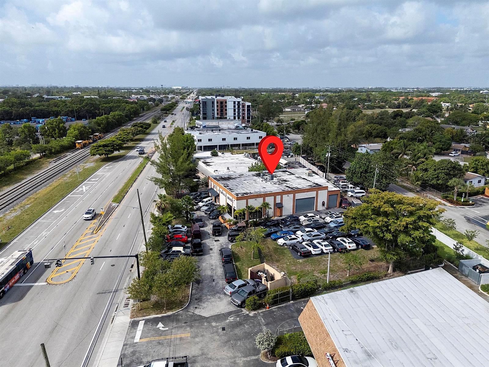 An aerial view shows a commercial building with a car lot and nearby railroad tracks — 4071 N Dixie Highway, Deerfield Beach FL 33064, DEERFIELD BEACH, FL