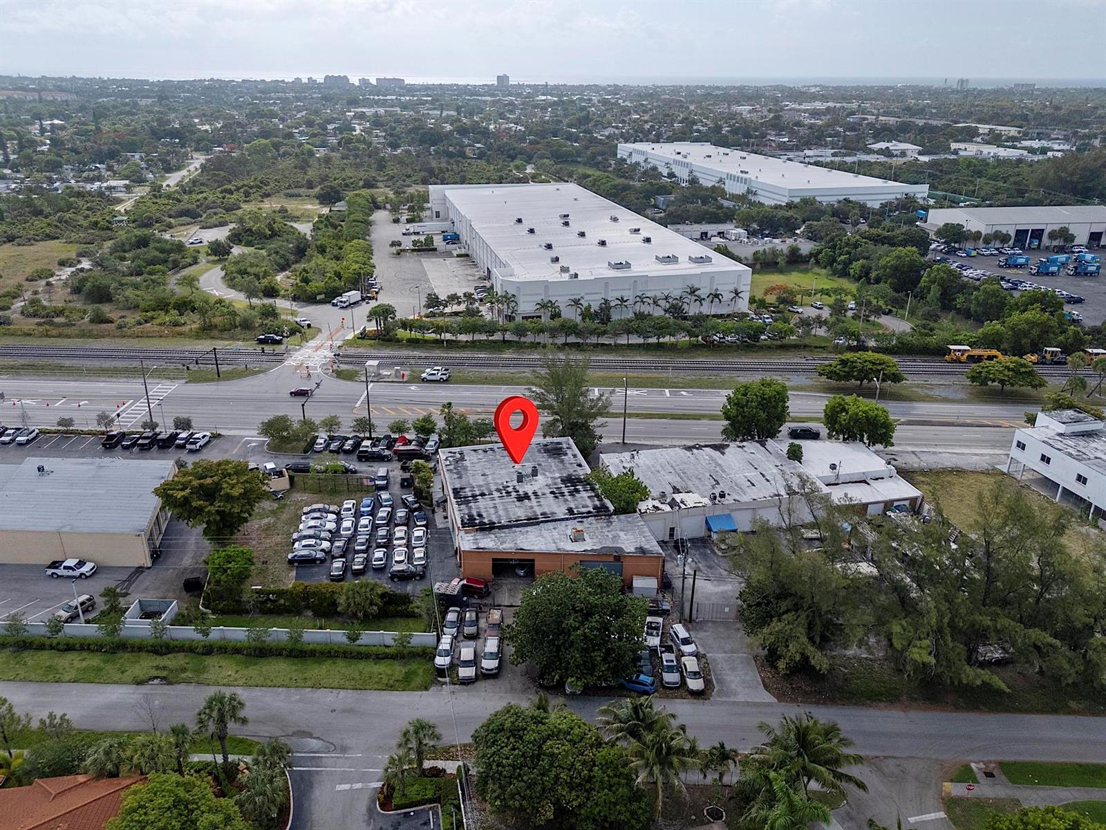 An aerial view shows a commercial building with a parking lot and a nearby warehouse — 4071 N Dixie Highway, Deerfield Beach FL 33064, DEERFIELD BEACH, FL