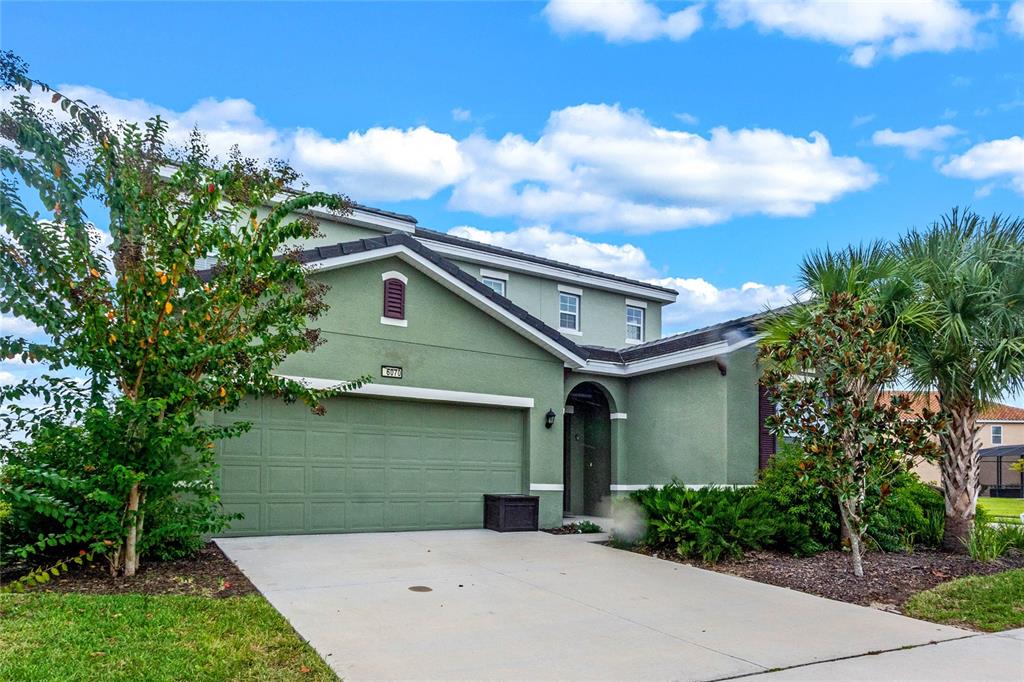 A two-story green house with a two-car garage and a concrete driveway — 6070 BROAD OAK DRIVE, DAVENPORT, FL
