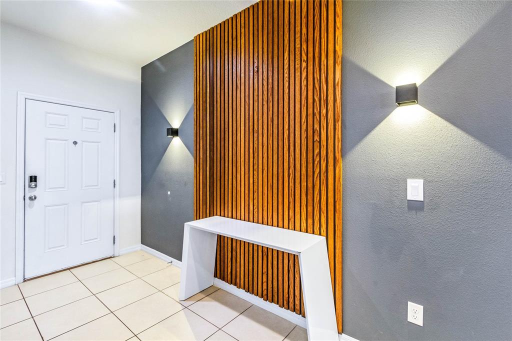An entryway features a white console table against a wood-slat accent wall with wall sconces — 6070 BROAD OAK DRIVE, DAVENPORT, FL