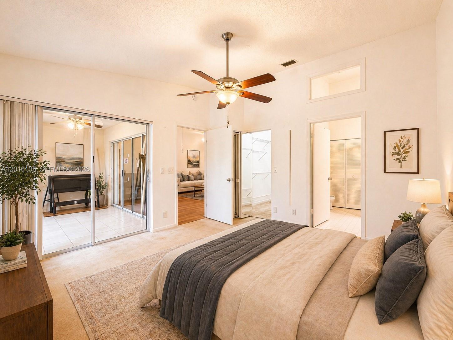 A bedroom features a ceiling fan, sliding glass doors to a patio, and two doorways — 5016 Rose Hill Dr # 2303, Boynton Beach FL 33437, BOYNTON BEACH, FL