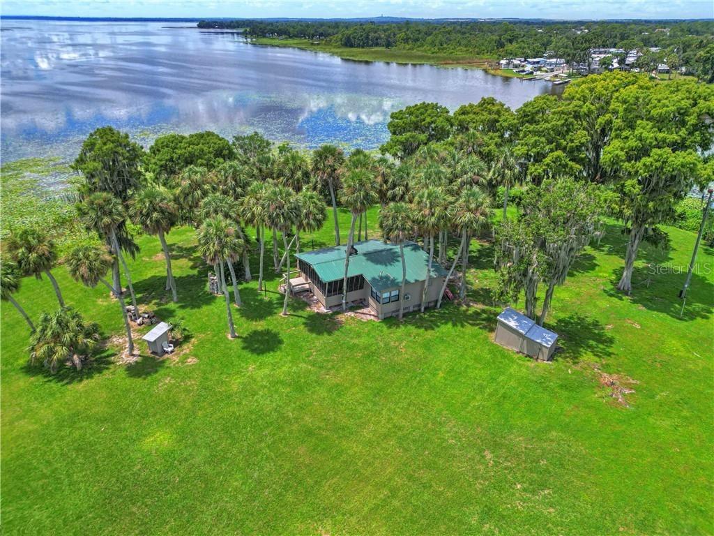 An aerial view shows a house with a green roof surrounded by trees near water — 0 JENNINGS FISH CAMP ROAD, LAKE WALES, FL