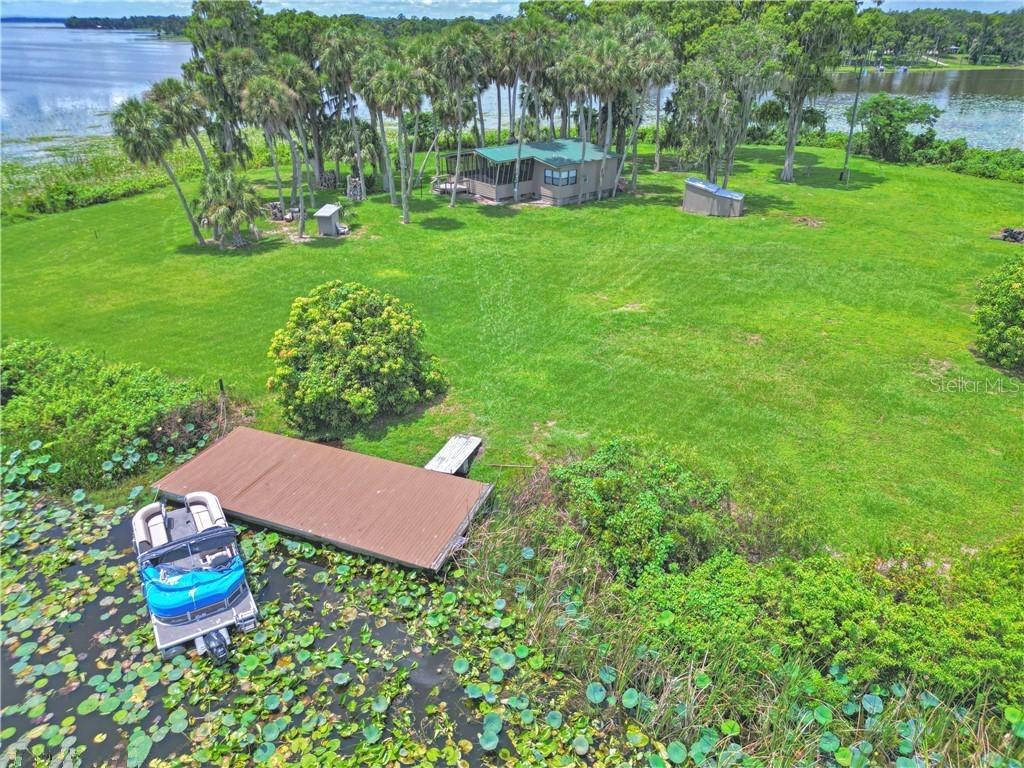 An aerial view shows a house with a dock and boat on a grassy lakefront lot — 0 JENNINGS FISH CAMP ROAD, LAKE WALES, FL