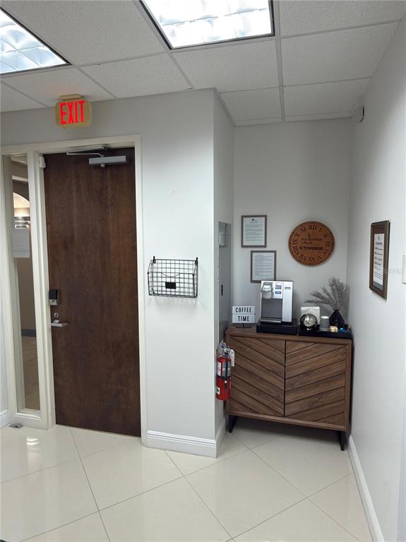 An office interior features a wooden door, a coffee station on a cabinet, and tile flooring — 6735 CONROY ROAD UNIT 420, ORLANDO, FL