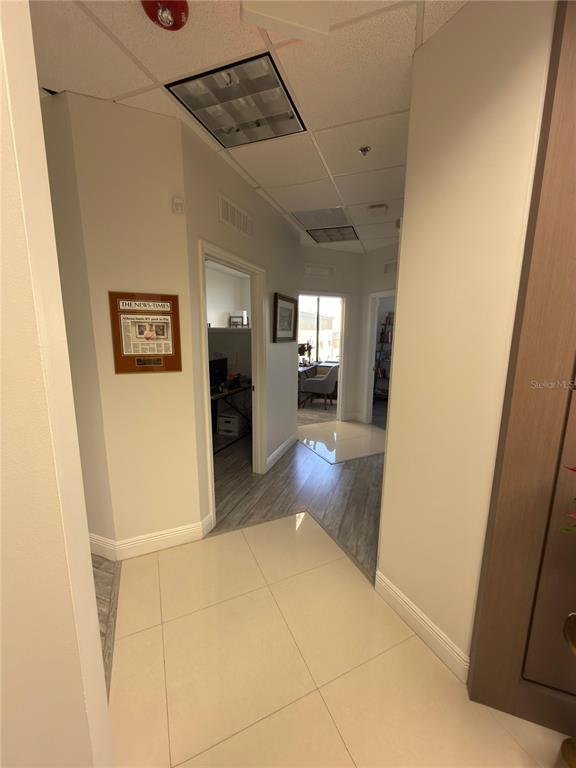 A view of an office hallway with light-colored tile flooring and gray wood-look flooring — 6735 CONROY ROAD UNIT 420, ORLANDO, FL