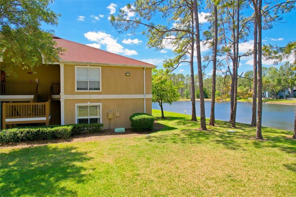 A multi-story apartment building exterior sits next to a grassy lawn and a lake — 9481 HIGHLAND OAK DRIVE UNIT 1112, TAMPA, FL