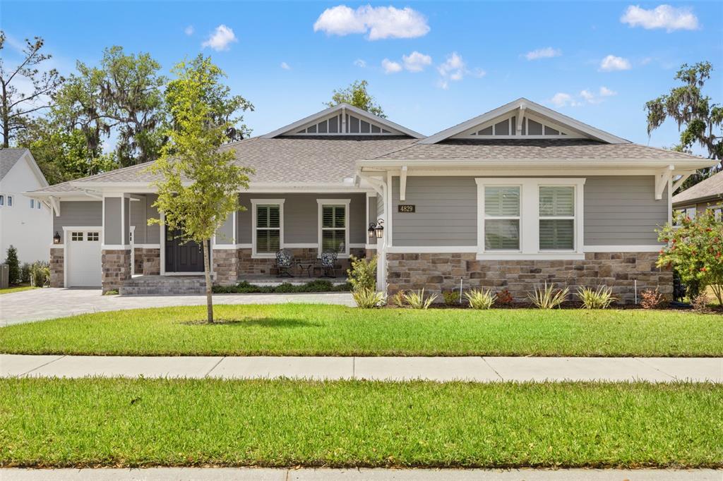 A single-story house with gray siding, stone veneer, and a covered front porch — 4829 HICKORY OAK DRIVE, BROOKSVILLE, FL