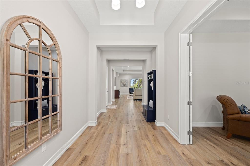 A modern kitchen features white cabinetry, a large central island with blue seating, and stainless appliances — 4829 HICKORY OAK DRIVE, BROOKSVILLE, FL
