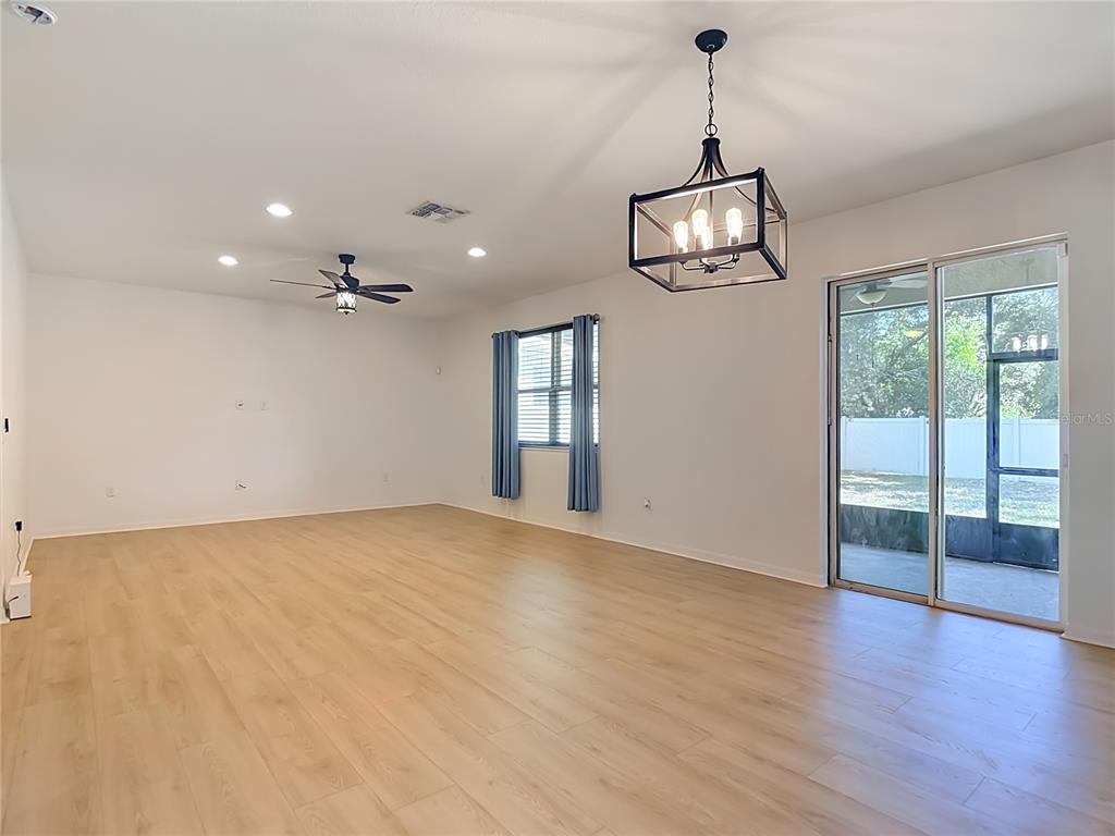 A spacious living area features light wood-look flooring, a ceiling fan, and a modern chandelier — 1113 CANYON OAKS DRIVE, BRANDON, FL